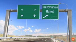 A green sign on a gantry over a motorway. One direction points to question marks and the turn off says "transformational moment"
