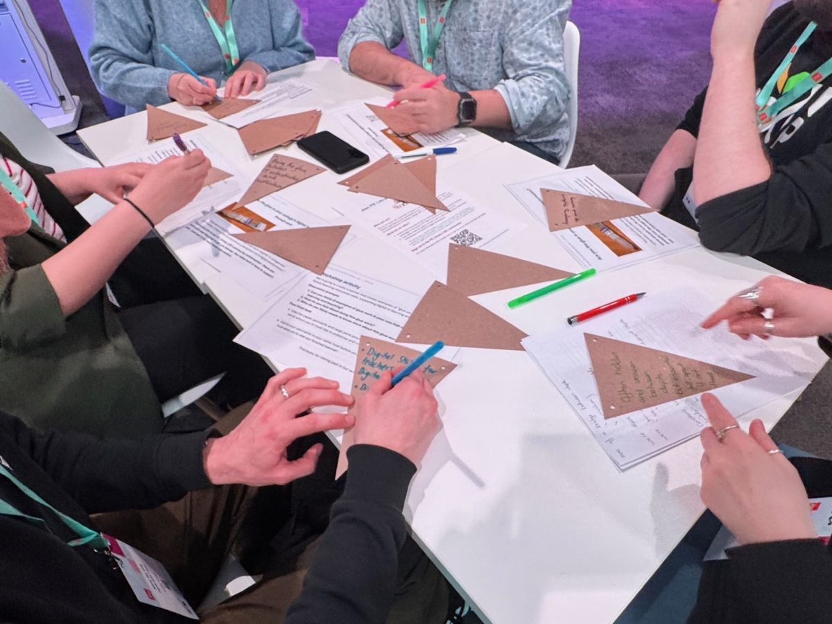 Group of people sitting around a table writing ideas on cards